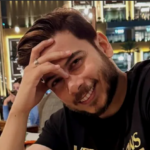 Man smiling with hand on forehead wearing a black T-shirt