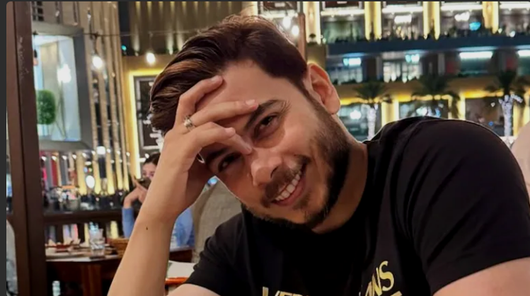 Man smiling with hand on forehead wearing a black T-shirt